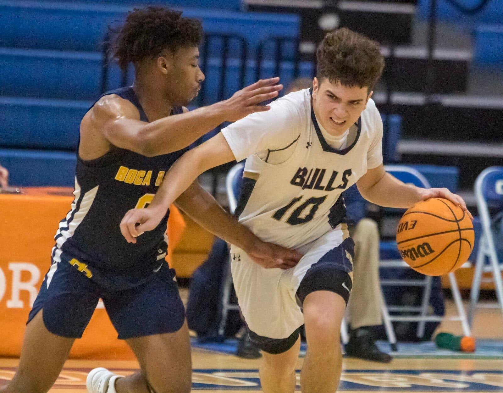 West Boca Bulls high school basketball player driving past a Boca High defender