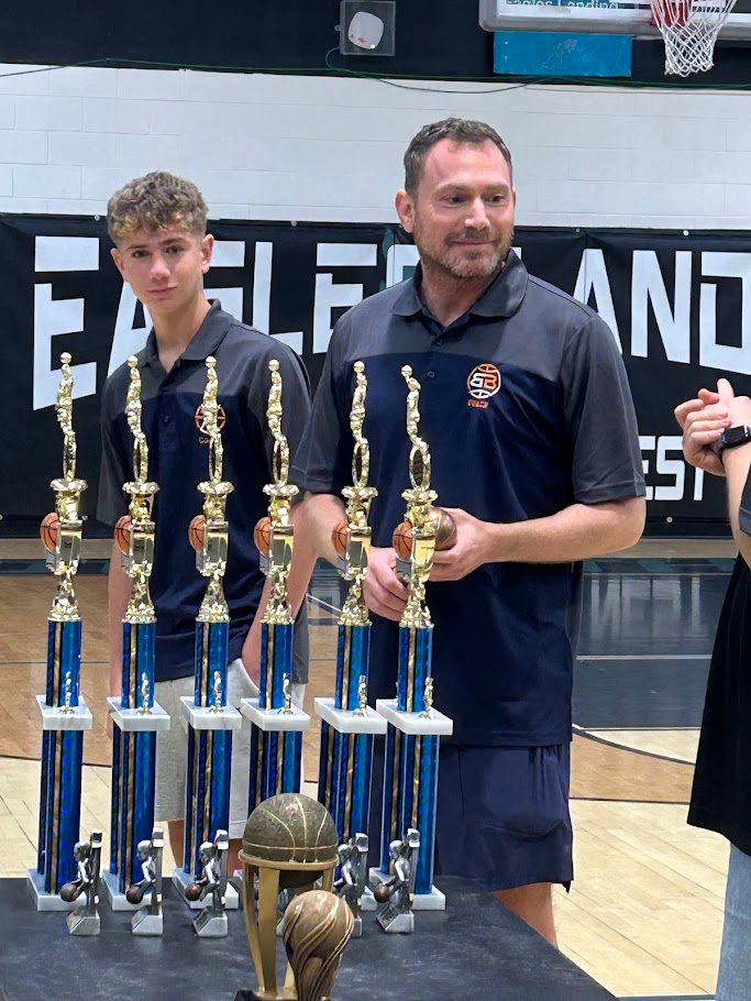 Boca Basketball coach standing with championship trophies at end of season awards