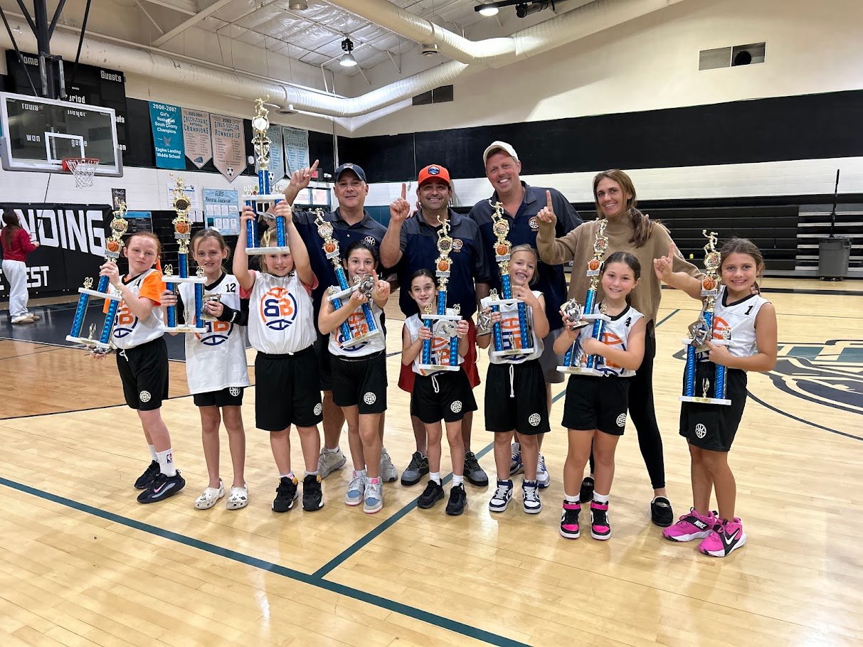 Boca Basketball girls championship team holding trophies at Boca Raton gym